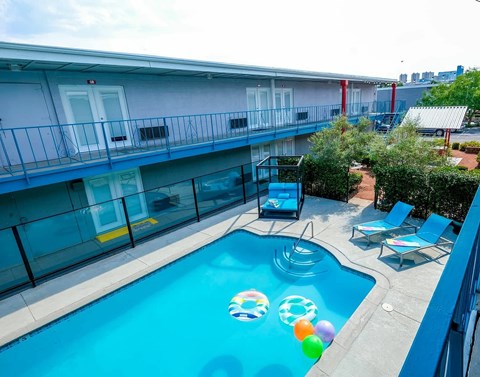 A pool with a blue tint and a few inflatable balls floating in it.