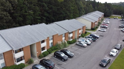 A parking lot in front of a building with cars parked.