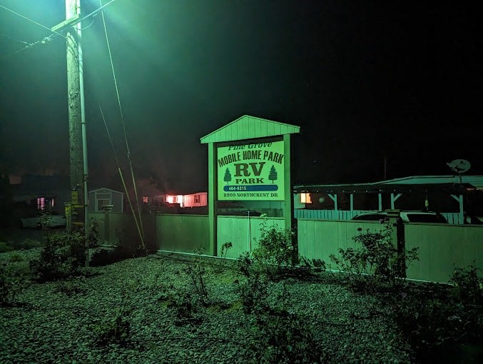 A sign for a home park RV park is lit up at night.