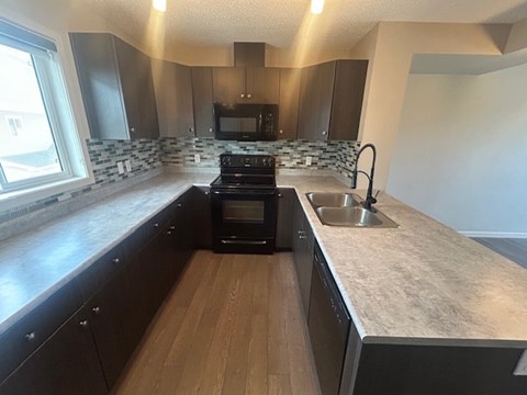A kitchen with a black stove top oven and a sink.
