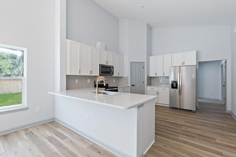 A kitchen with white cabinets and a wooden floor.