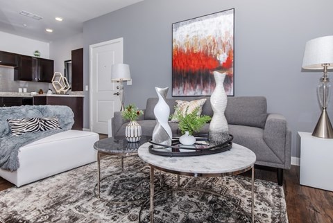 A living room with a grey couch, a coffee table, and a painting on the wall.