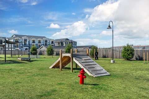 A playground with a red fire hydrant in the foreground.