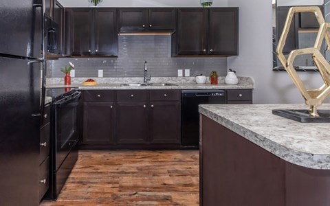 A kitchen with dark wood cabinets and a black refrigerator.