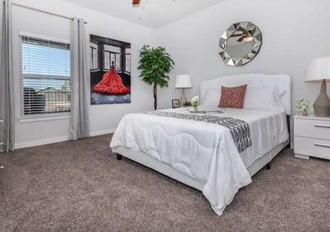 A bedroom with a large bed, a potted plant, and a mirror on the wall.