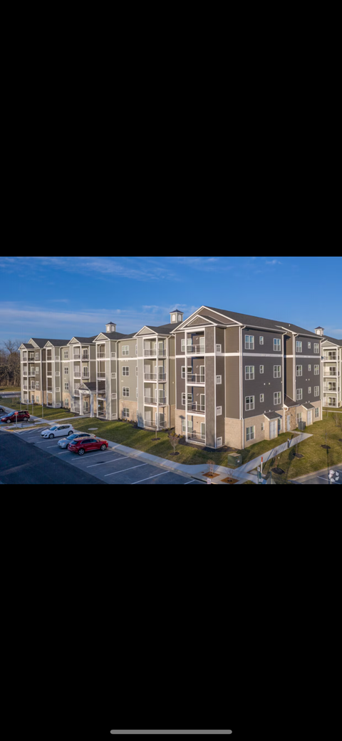A large apartment complex with multiple buildings and cars parked in the parking lot.