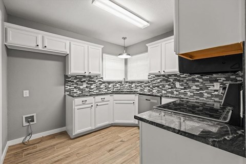 A kitchen with white cabinets and a black and white tiled backsplash.