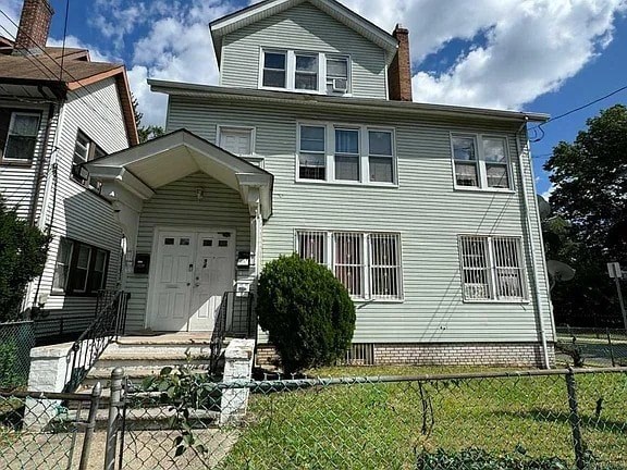 A two-story house with a white door and a small front yard.