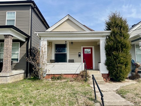 A house with a red door is surrounded by a small front yard.