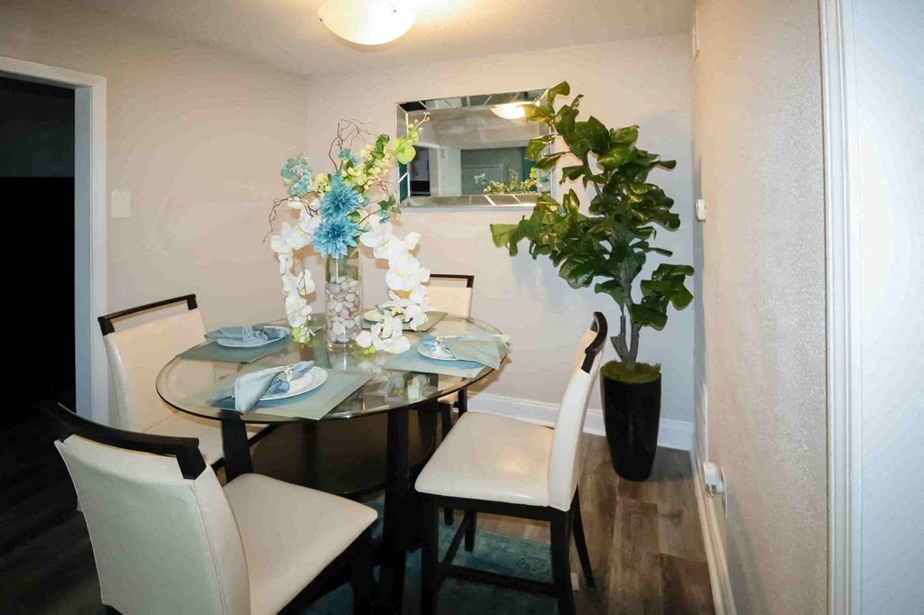 A dining table with chairs and a vase with flowers.