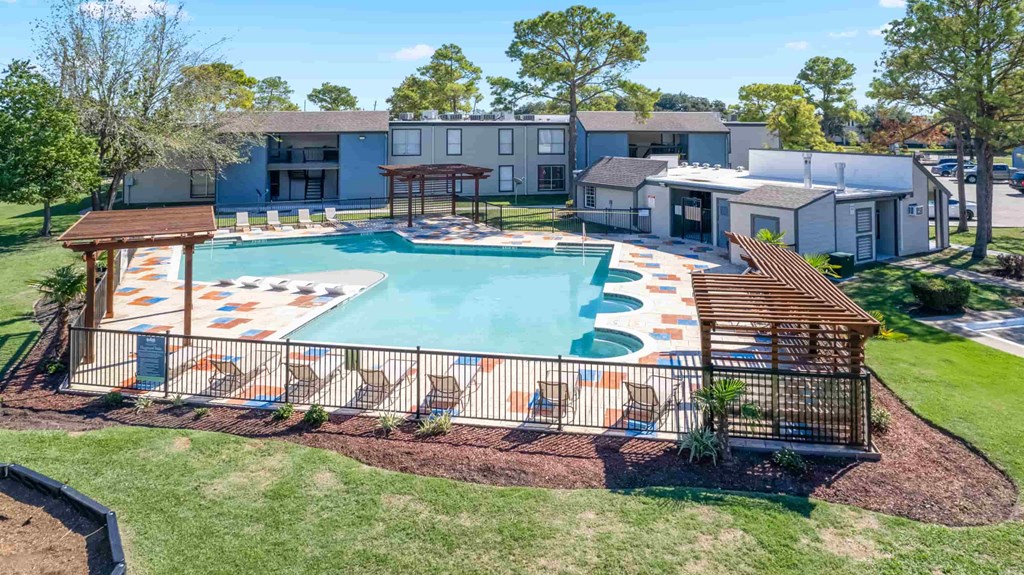 A swimming pool with a wooden deck and a building in the background.