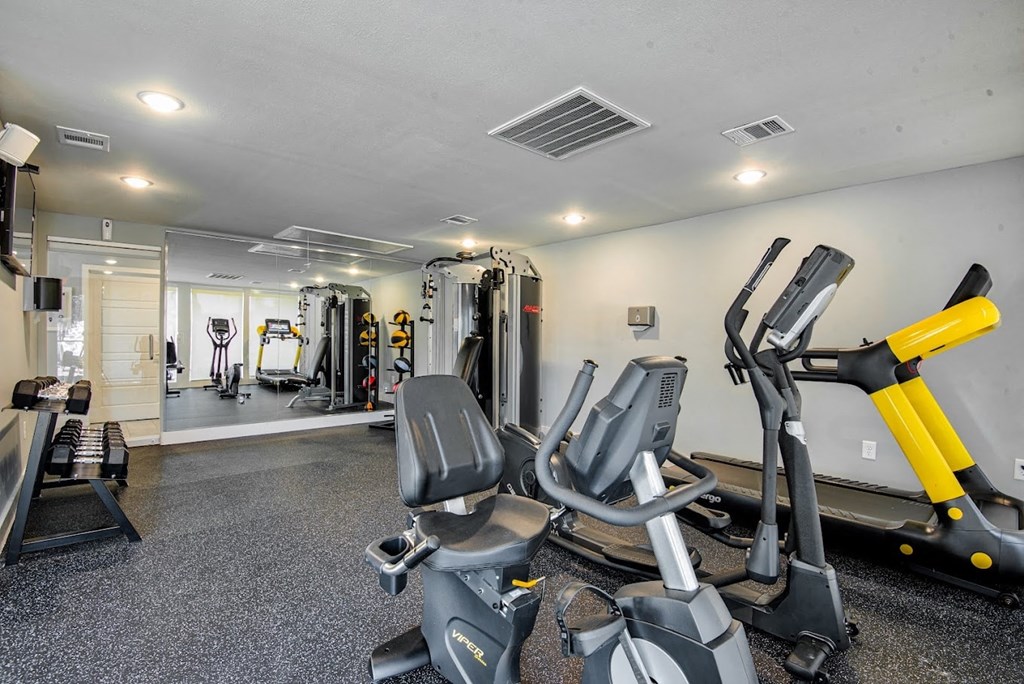 A gym with a variety of exercise equipment including treadmills, stationary bikes, and weight machines.