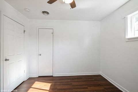 A room with a ceiling fan and two doors.