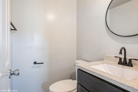 A bathroom with a white toilet and a sink with a black faucet.
