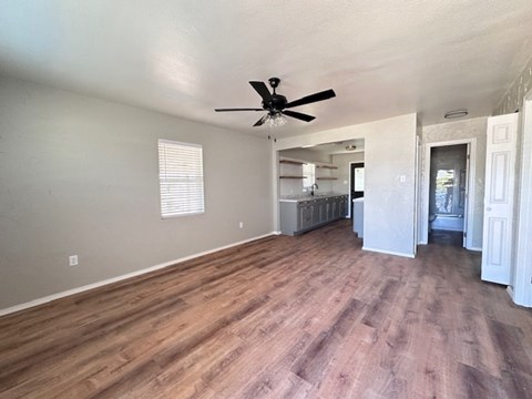A room with a ceiling fan and wooden flooring.