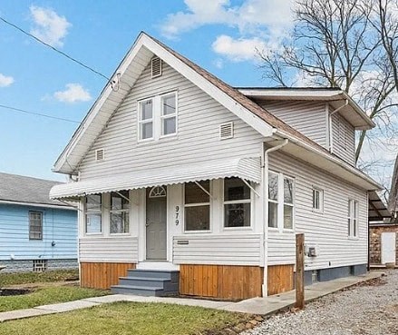 A two-story house with a grey and white exterior and a brown front porch.