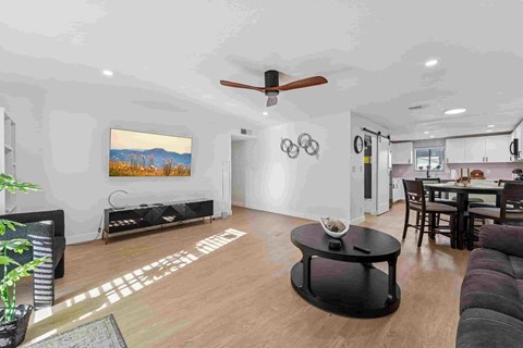 A living room with a black coffee table and a painting on the wall.