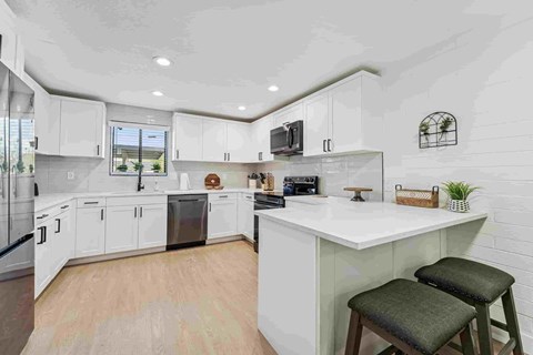 A kitchen with white cabinets and a large island with two stools.