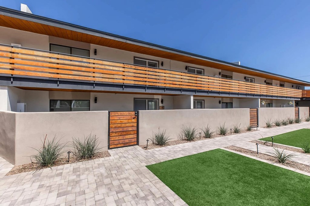 A modern building with a wooden door and a green lawn in front.