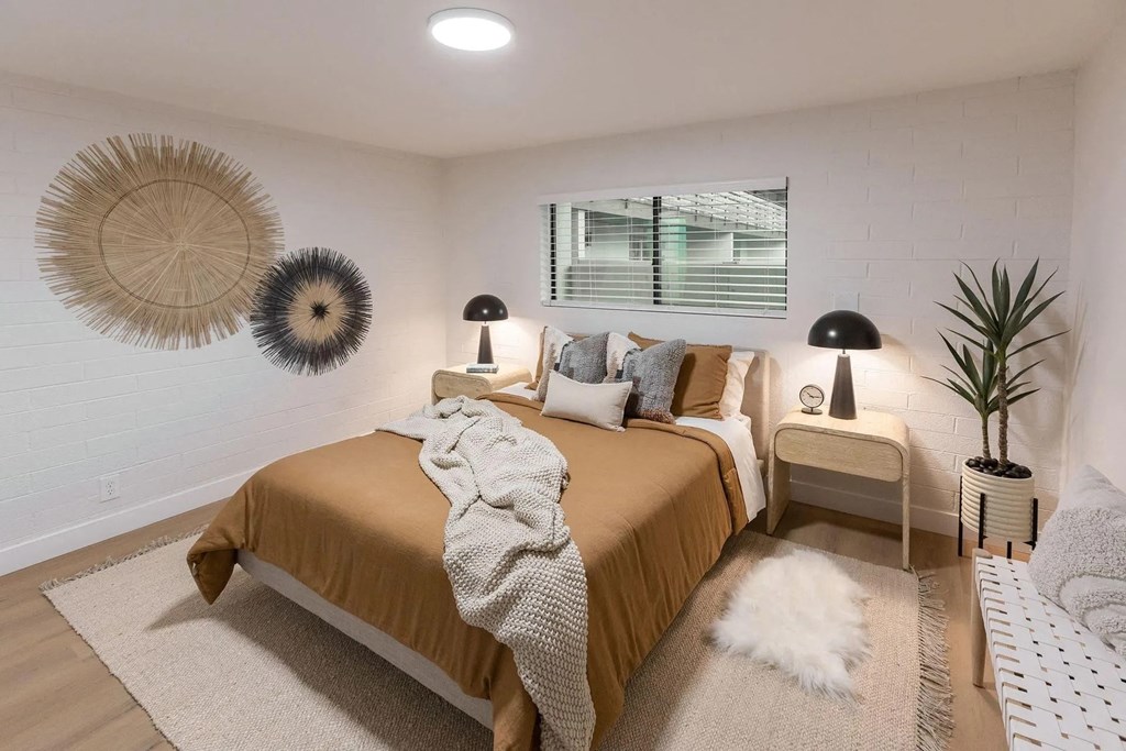 A bedroom with a bed in the center and two lamps on the side tables.