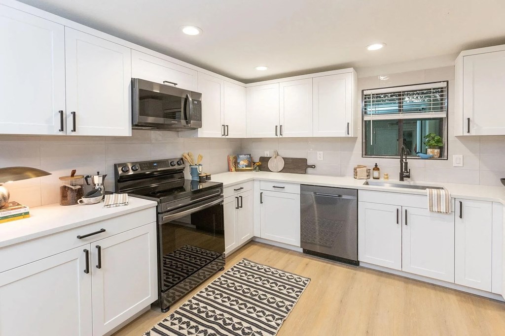 A modern kitchen with white cabinets and black appliances.