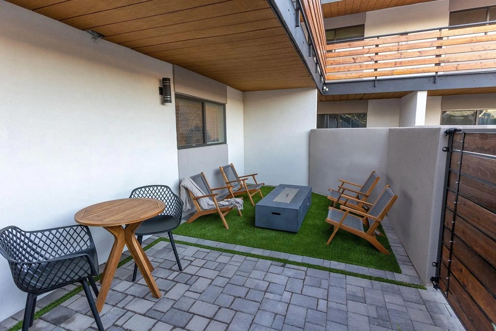 A patio with a black chair, a wooden table, and a small wooden box.