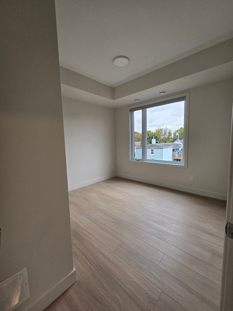 A room with a window and a wooden floor.