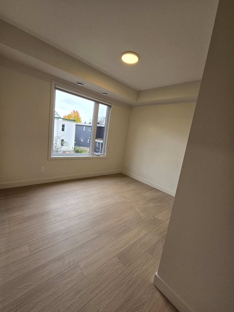A room with a window and wooden flooring.