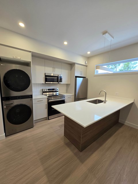 A modern kitchen with a white countertop and wooden flooring.
