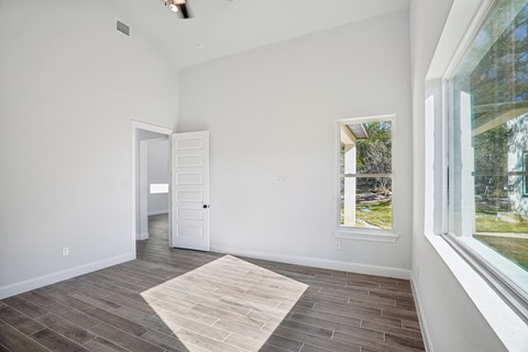 A room with a rug on the floor and a window showing a view of trees.