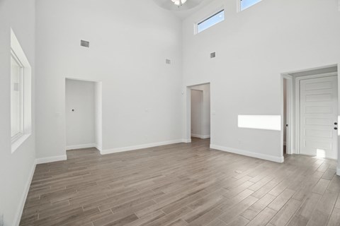A spacious room with wooden flooring and white walls.