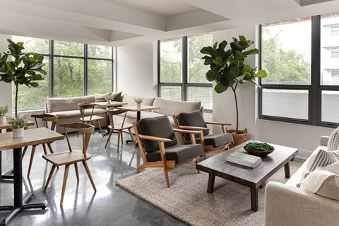 A living room with a large window and a variety of chairs and tables.
