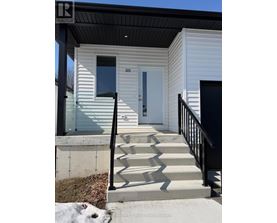 A small white house with a black railing and steps leading to a white door.