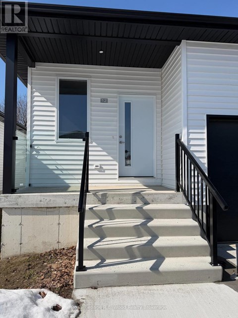 A small white house with a black railing and steps leading to a white door.