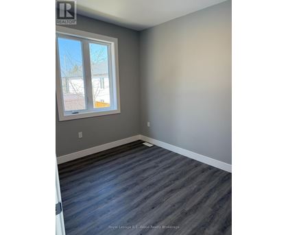 A room with a grey wall and a window with a view of a tree and a building outside.