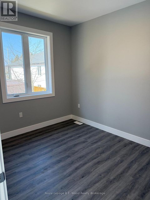 A room with a grey wall and a window with a view of a tree and a building outside.