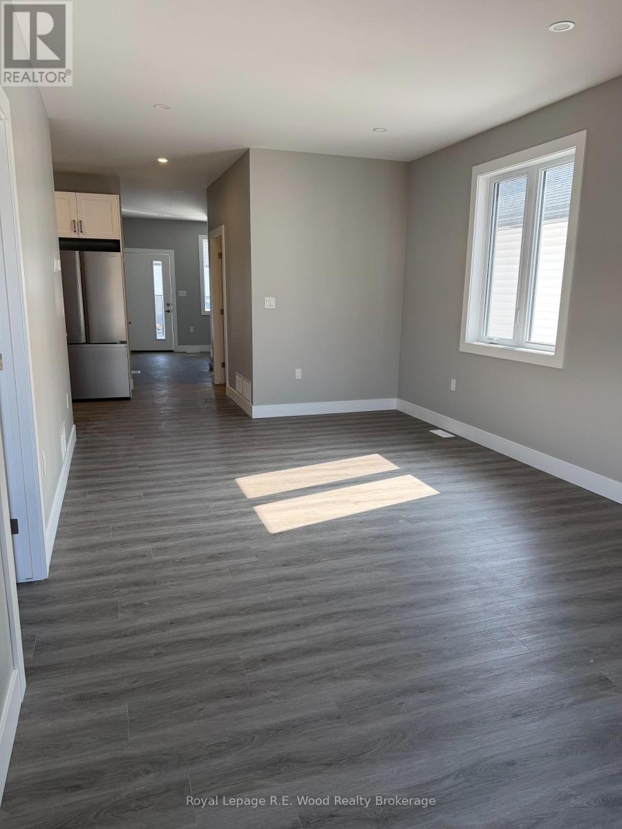 A spacious room with wood flooring and a window.