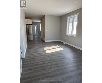 A spacious room with wood flooring and a window.