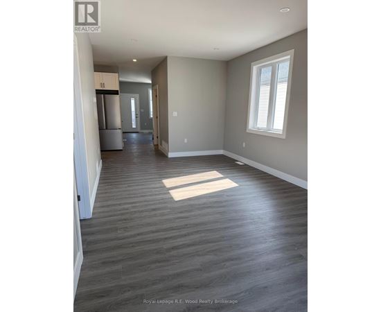 A spacious room with wood flooring and a window.