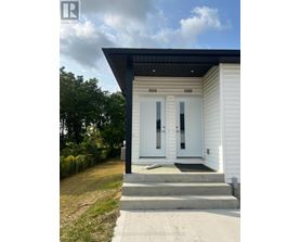 A white house with a black roof and a glass door.