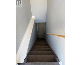A staircase with a wooden handrail and a white wall on the side.