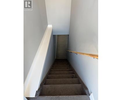 A staircase with a wooden handrail and a white wall on the side.
