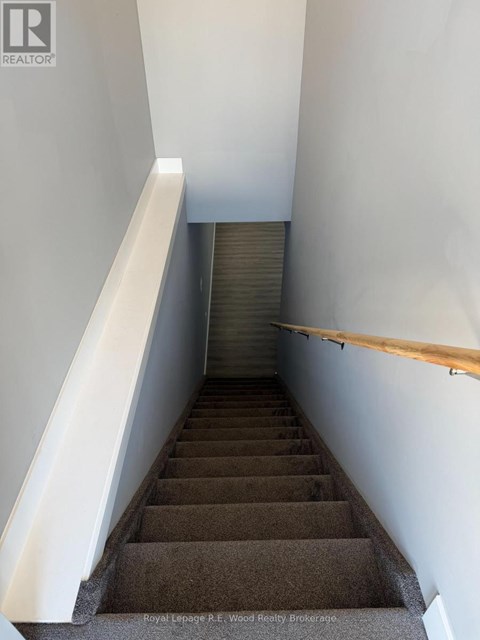 A staircase with a wooden handrail and a white wall on the side.