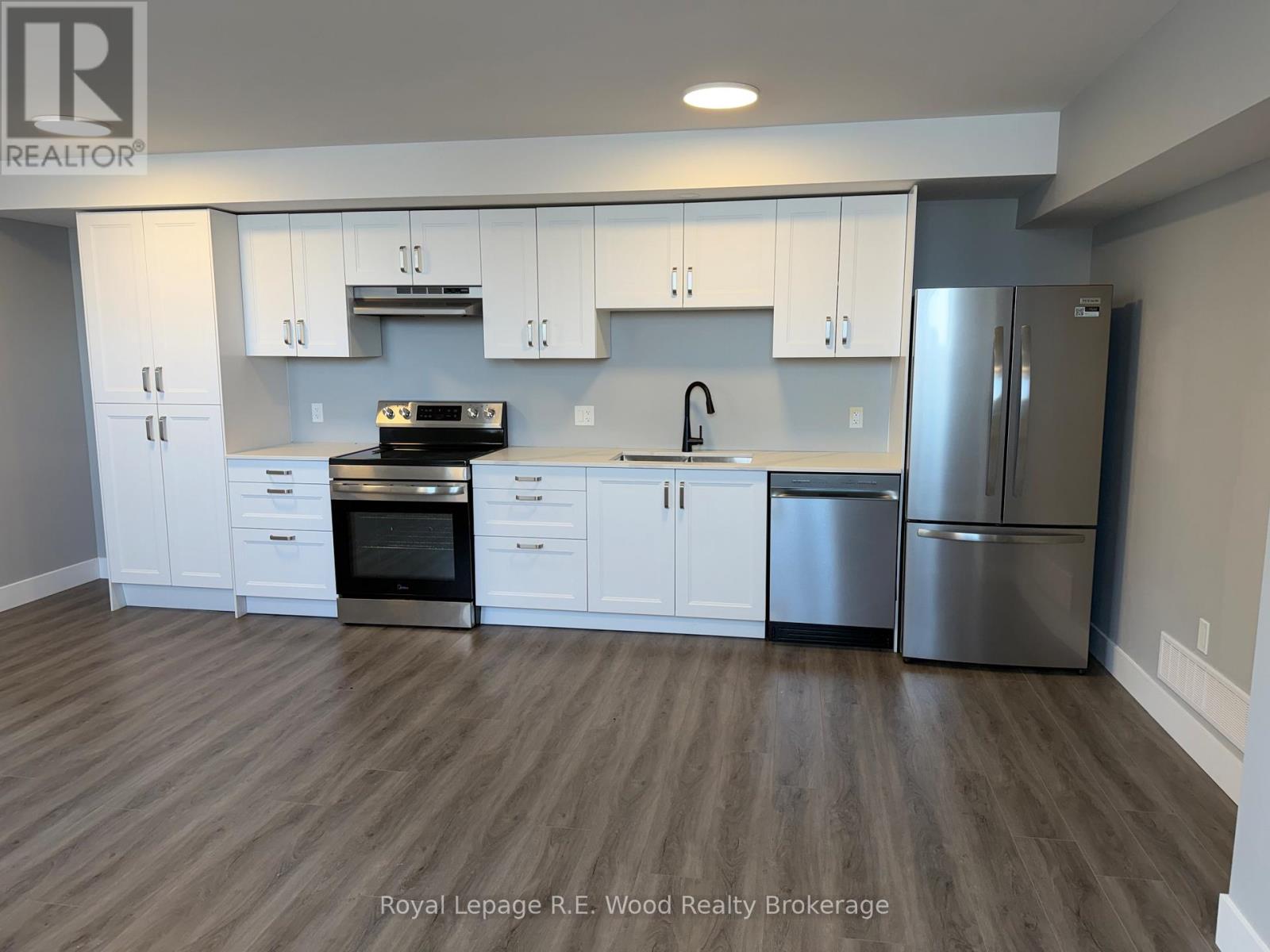 A modern kitchen with white cabinets and stainless steel appliances.