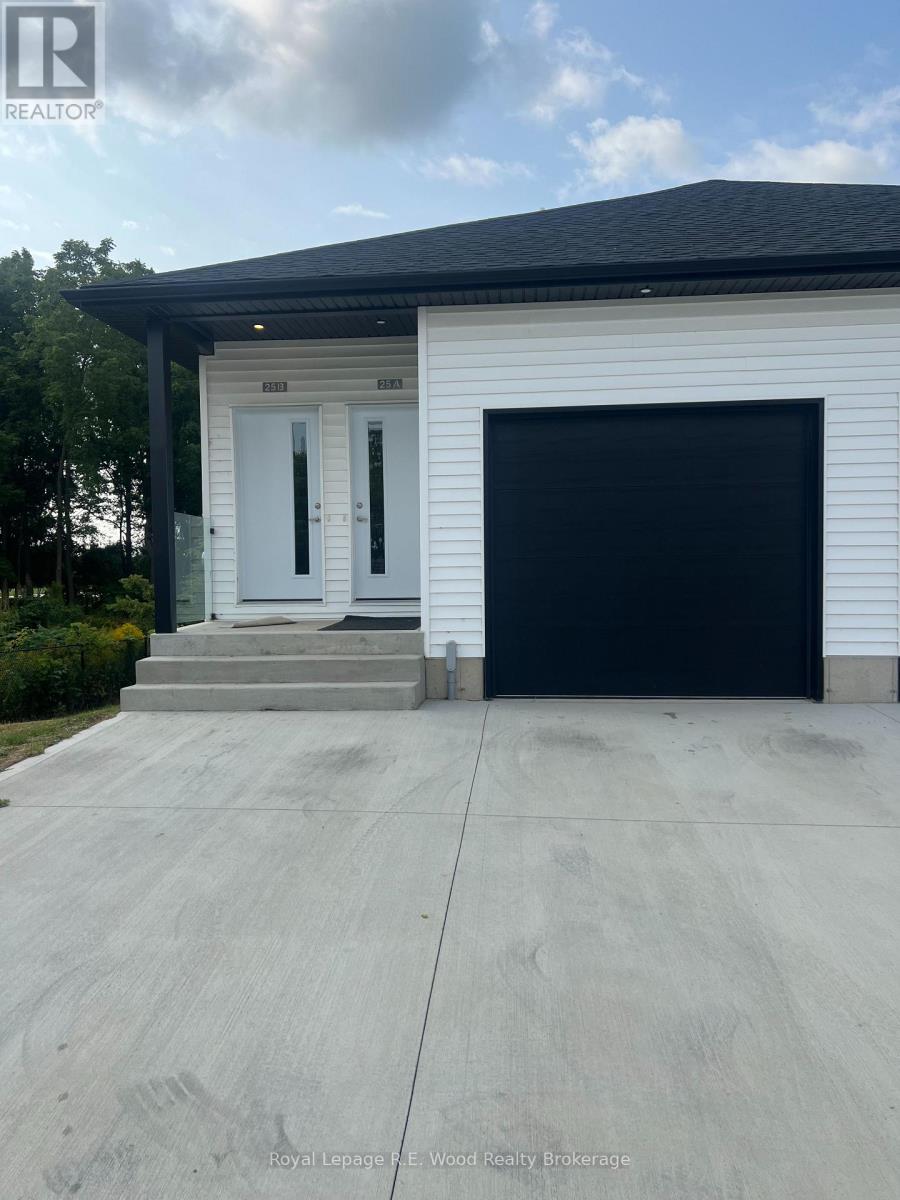 A white house with a black garage door and a realtor logo on the top left.