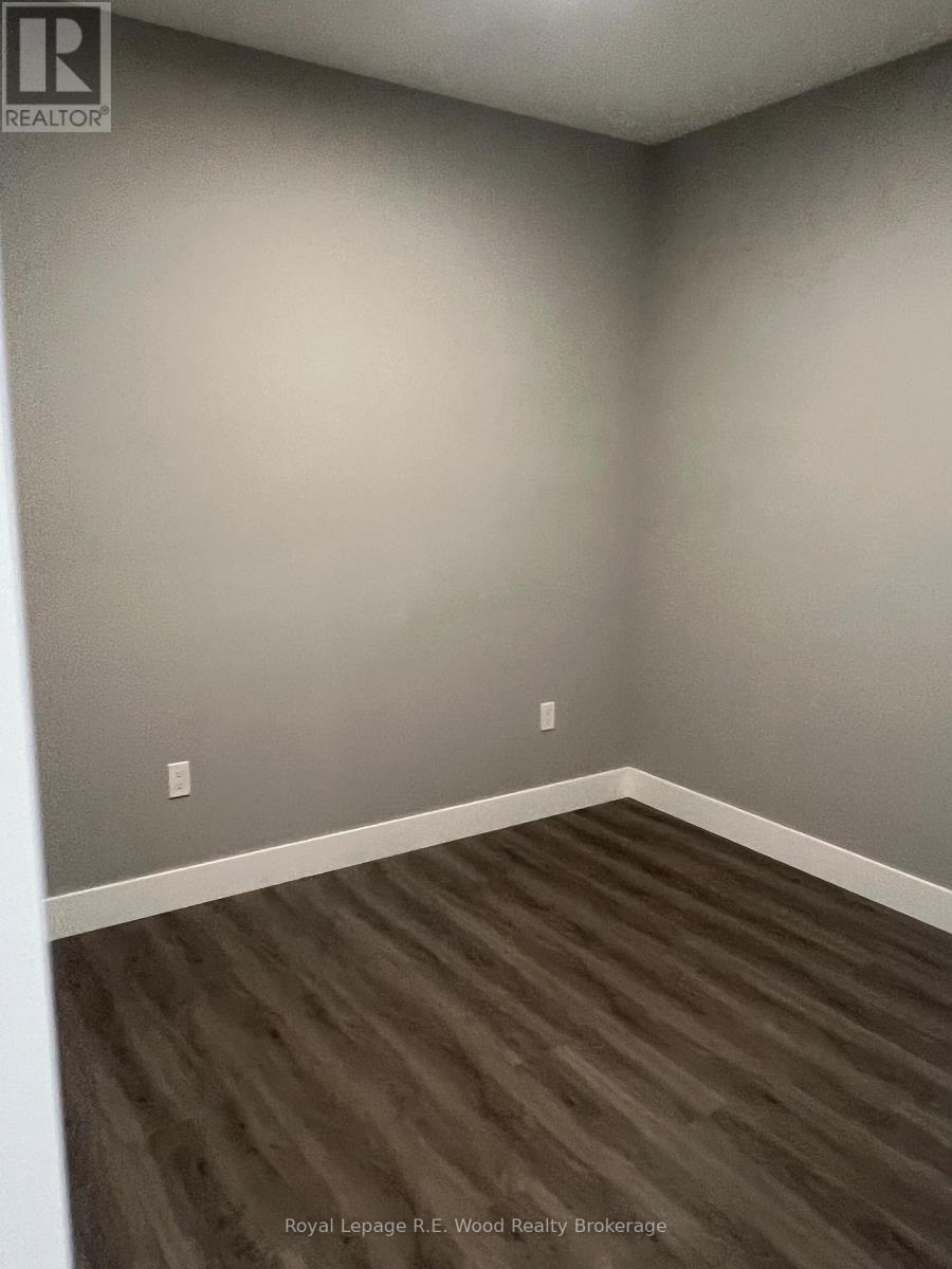A room with wooden flooring and a grey wall.