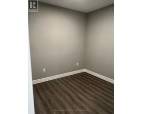 A room with wooden flooring and a grey wall.