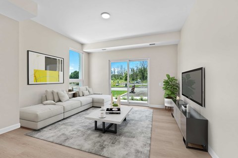 A modern living room with a white sofa, a grey rug, and a large window.
