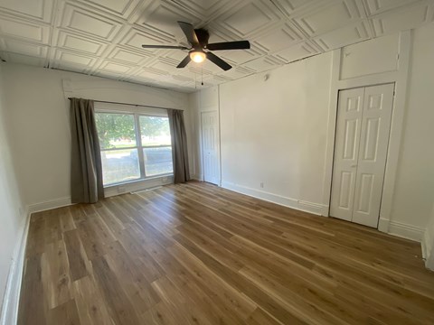 A room with a ceiling fan and wooden flooring.