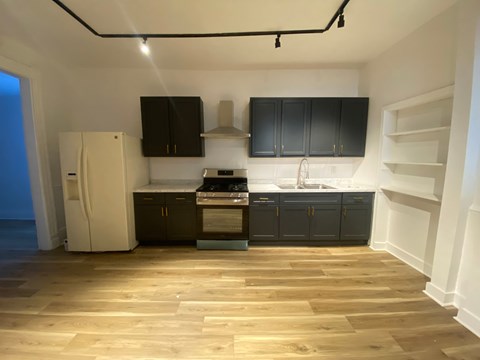 A kitchen with black cabinets and a white fridge.